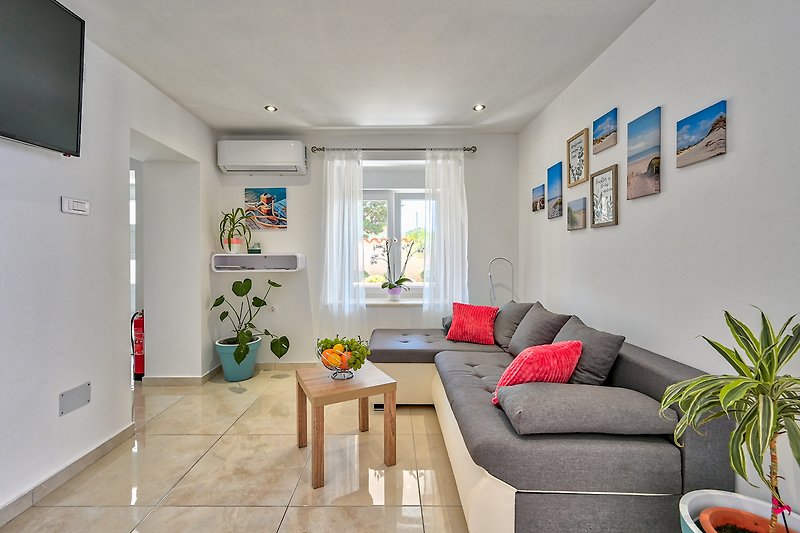 Gemütliches Wohnzimmer mit bequemen Möbeln und grünen Pflanzen.