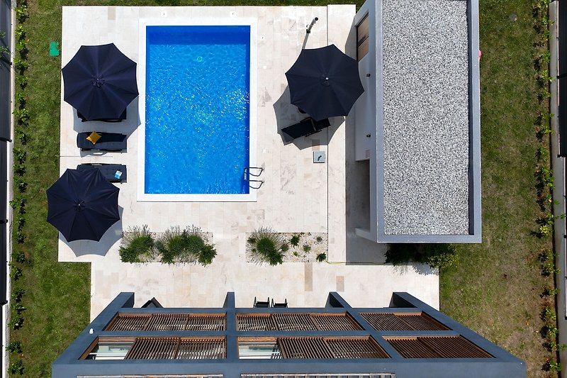 Moderne Immobilie mit blauem Himmel, urbanem Design und gepflegtem Garten. Perfekt für erholsame Ferien.