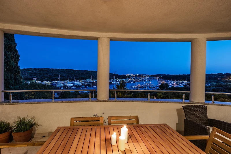 Villa mit Balkon, Holzstühlen und Blick auf das Resort.