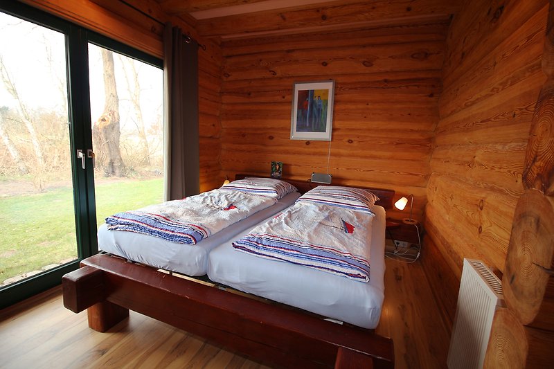 Gemütliches Schlafzimmer mit Holzbett und Fensterblick.