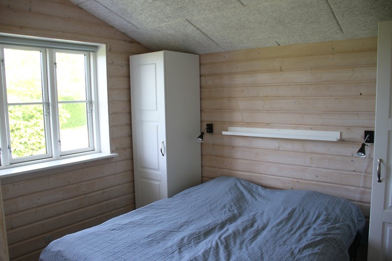 Gemütliches Schlafzimmer mit stilvollem Holzbett und Fenster.