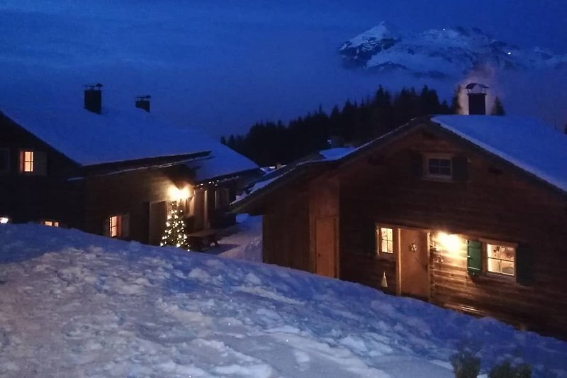 Ein winterliches Bergdorf mit gemütlicher Hütte und verschneiten Bäumen.