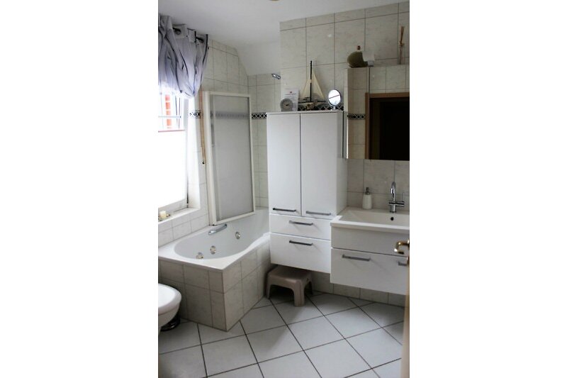 Badezimmer mit Badewanne/Dusche, Spiegel und Waschbecken