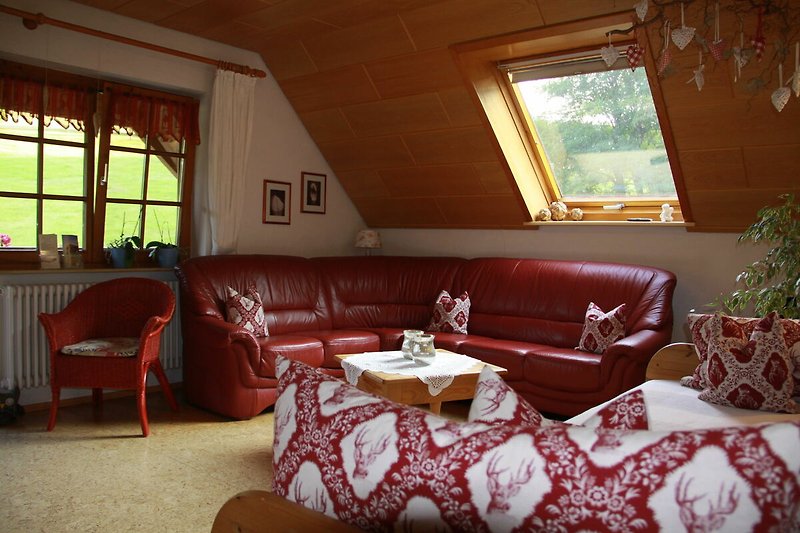 Gemütliches Wohnzimmer mit bequemer Couch, Holzmöbeln und Fenster mit schöner Aussicht.
