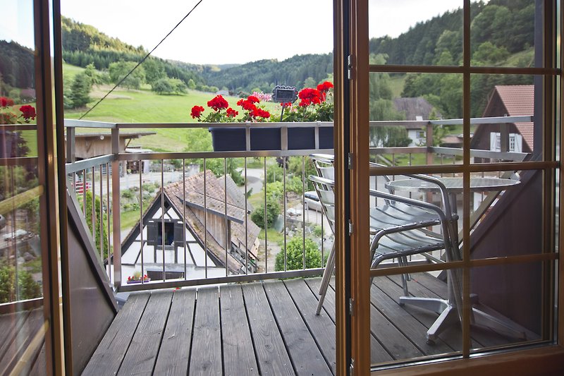 Gemütliches Ferienhaus mit Bergblick, Holzmöbeln und blühenden Pflanzen.