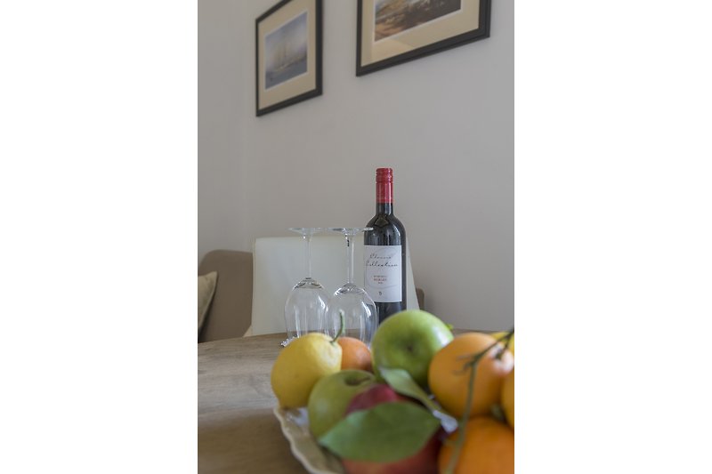 Gemütliche Mahlzeit mit Wein und Obst auf Holztisch.