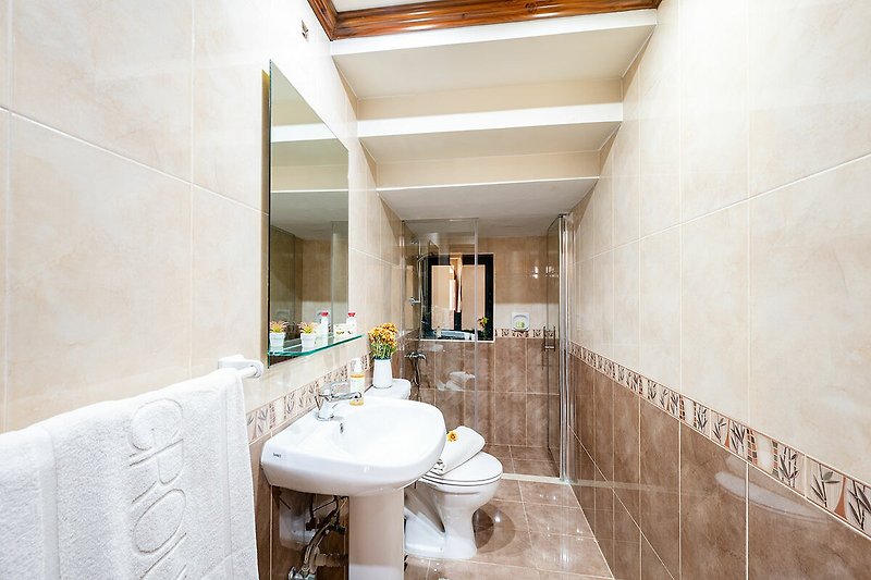 Modernes Badezimmer mit Spiegel, Armatur und Fliesen.