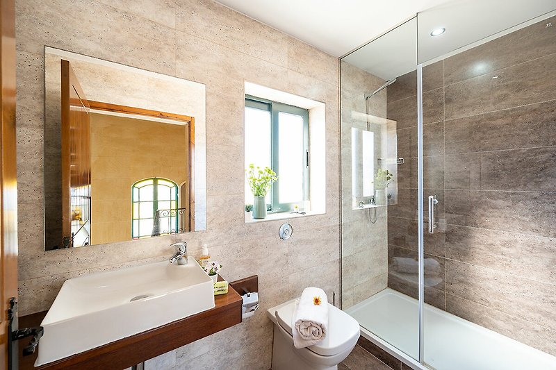 Modernes Badezimmer mit Spiegel, Armatur, Pflanze und Badewanne.