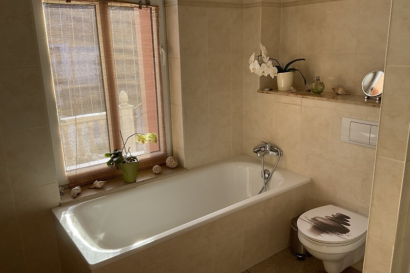 Schönes Badezimmer mit Badewanne, Fenster und Fliesen.