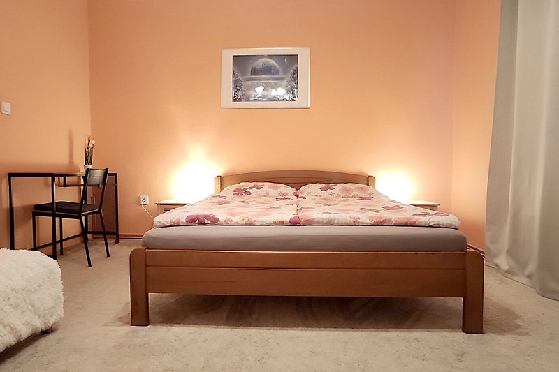 Gemütliches Schlafzimmer mit Holzmöbeln, Bettwäsche und warmem Licht.