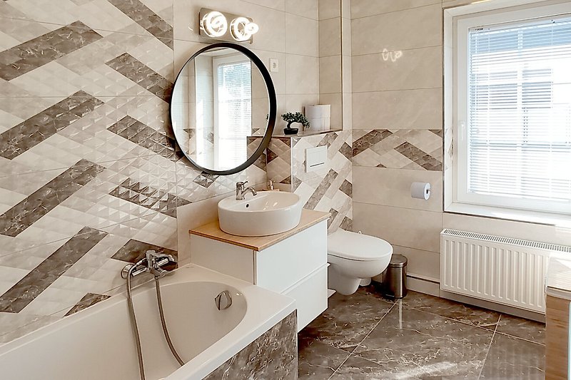 Ein stilvolles Badezimmer mit Spiegel, Waschbecken und Fenster.