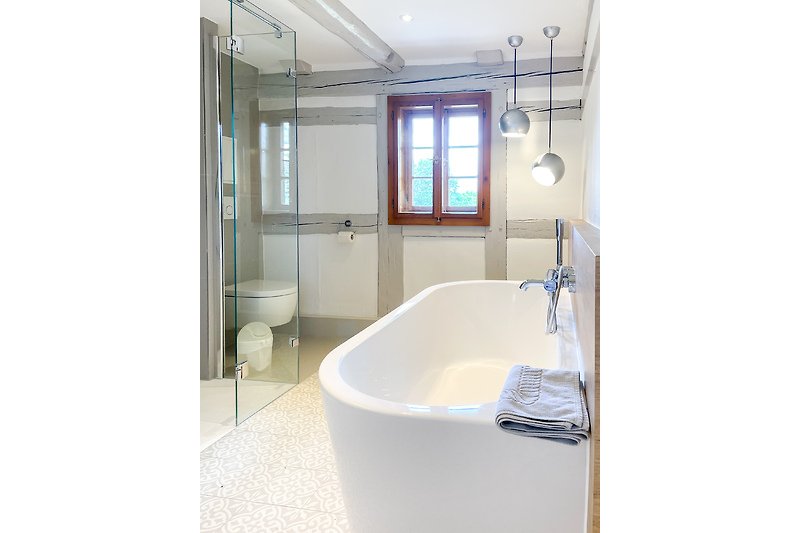Ein modernes Badezimmer mit Badewanne, Dusche und Fenster.