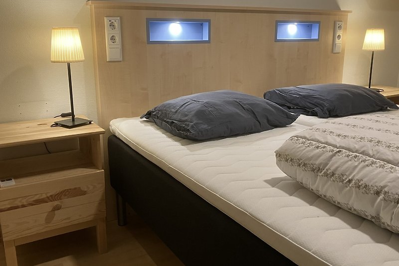 Schlafzimmer mit stilvoller Beleuchtung und gemütlichem Boxspring Betten