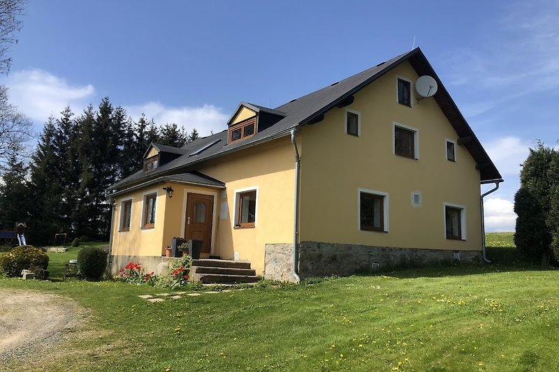 Charmantes Landhaus mit Garten, Bäumen und Holzfassade.