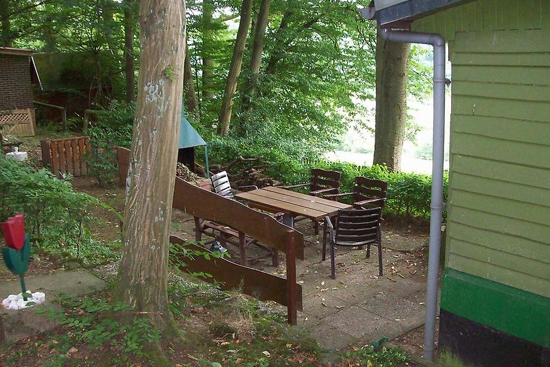 Holzhaus mit Gartenmöbeln und grüner Landschaft.