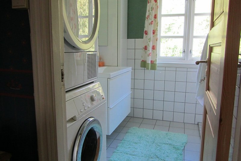 Moderne Waschküche mit Fenster, Waschmaschine und Trockner.