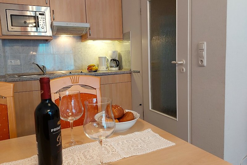 Küche mit Weinflaschen, Gläsern und Geschirr. Gemütliche Baratmosphäre.