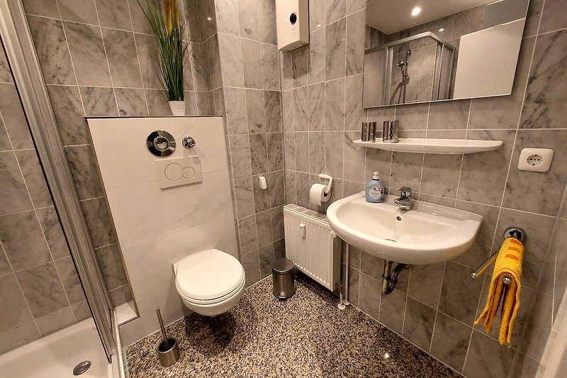 Badezimmer mit lila Akzenten, Spiegel und Pflanze.