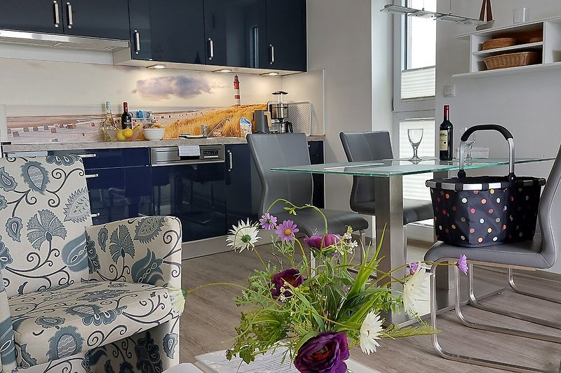 Wohnzimmer mit lila Dekoration, Blumenarrangement und Küchentisch.