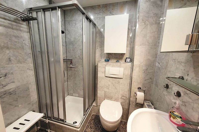 Badezimmer mit Spiegel, Wasserhahn, Waschbecken und Toilette.