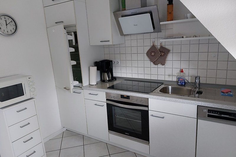 Moderne Küche mit weißen Schränken, grauer Arbeitsplatte und Gasofen.
