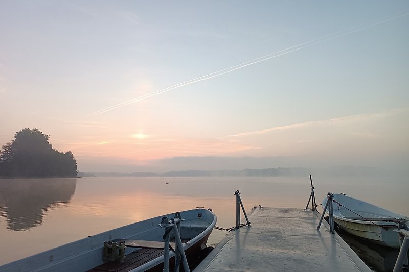 Boote auf einem ruhigen See bei Sonnenaufgang.