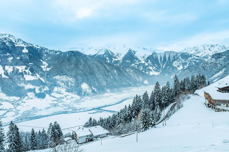 Berglandschaft mit schneebedeckten Gipfeln, Tannen und einer verschneiten Straße. Winterurlaub in den Bergen.