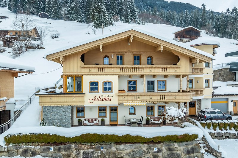 Winterliches Bergdorf mit verschneitem Haus, Fenstern und Tannenbaum. Perfekt für einen Winterurlaub.
