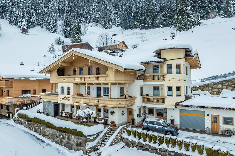 Berglandschaft mit verschneitem Haus, Fenster und Tannenbaum. Winterurlaub in den Bergen.