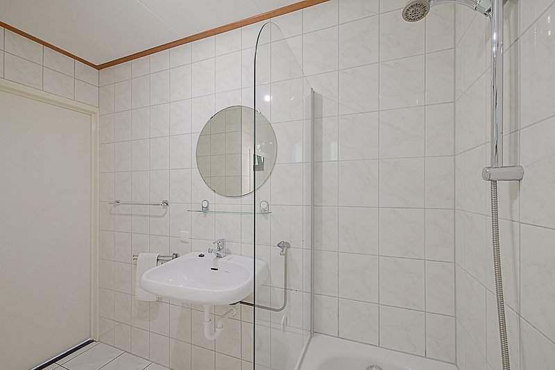 Modernes Badezimmer mit Dusche, Waschbecken und Fliesen.