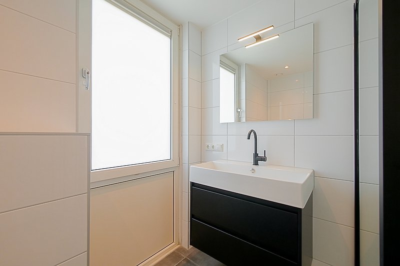 Modernes Badezimmer mit Glaswaschbecken, Holzschrank und Fliesen.
