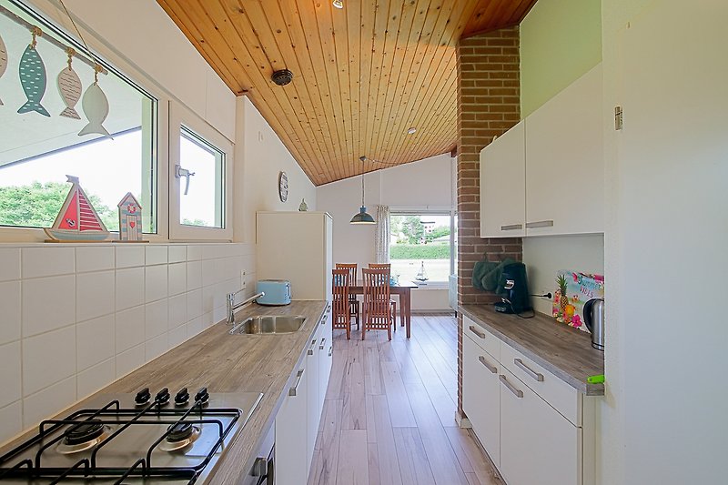 Küche mit Holzschränken, Fenster und Gasherd.