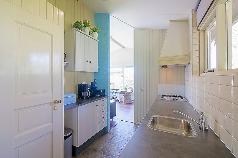 Stilvolle Küche mit Holzschränken, Spüle und Fenster.