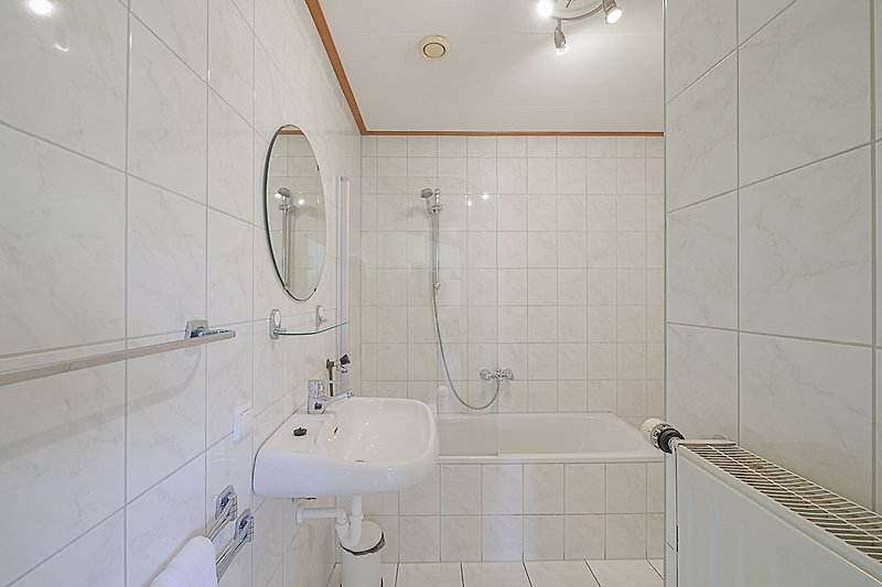 Modernes Badezimmer mit Badewanne, Dusche und Fliesen.