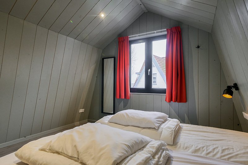 Schlafzimmer mit Holzbett, Vorhang und Lampe.