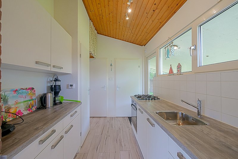 Moderne Küche mit Holzschränken, Spüle und Fenster.