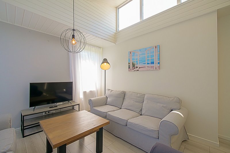Modernes Wohnzimmer mit Holzmöbeln und grauem Sofa.