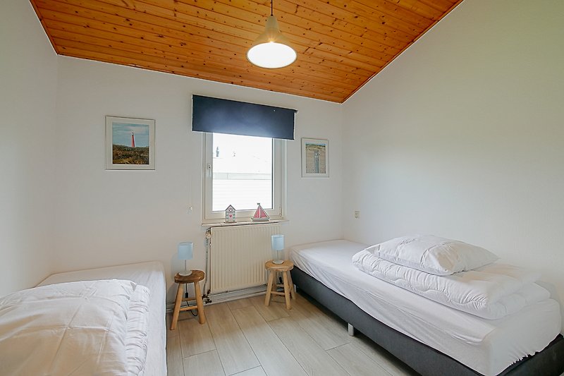 Schlafzimmer mit gemütlichem Bett, Lampen und Holzmöbeln.