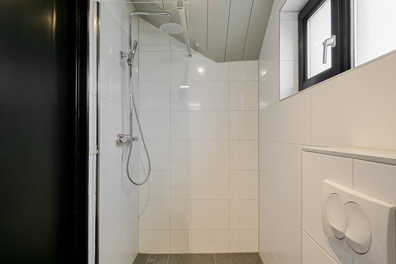Modernes Badezimmer mit Dusche, Toilette und Fenster.
