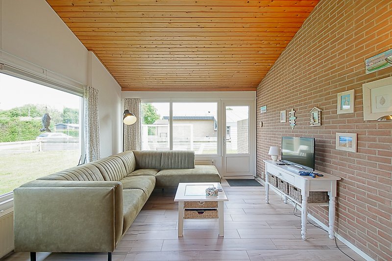 Wohnzimmer mit bequemer Couch, Holzmöbeln und Pflanzen.