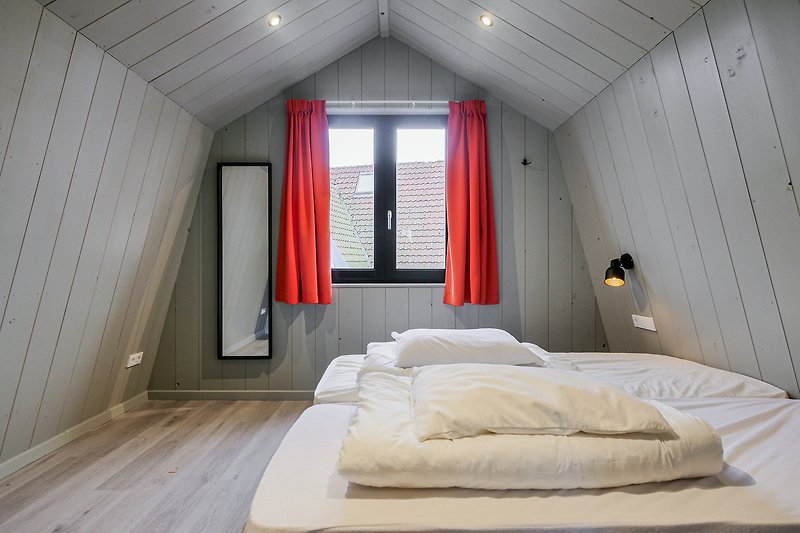 Schlafzimmer mit Holzbett, Vorhang, Lampe und Fenster.