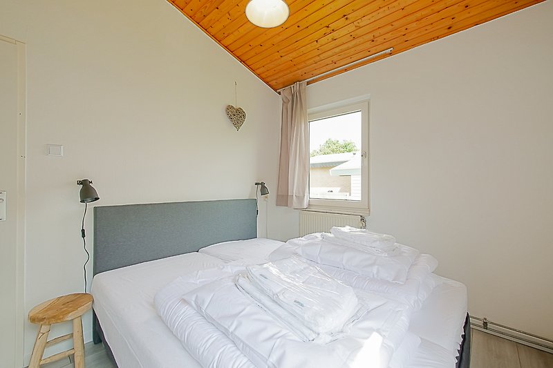 Schlafzimmer mit Holzbett, gemütlichen Kissen und blauer Wand.