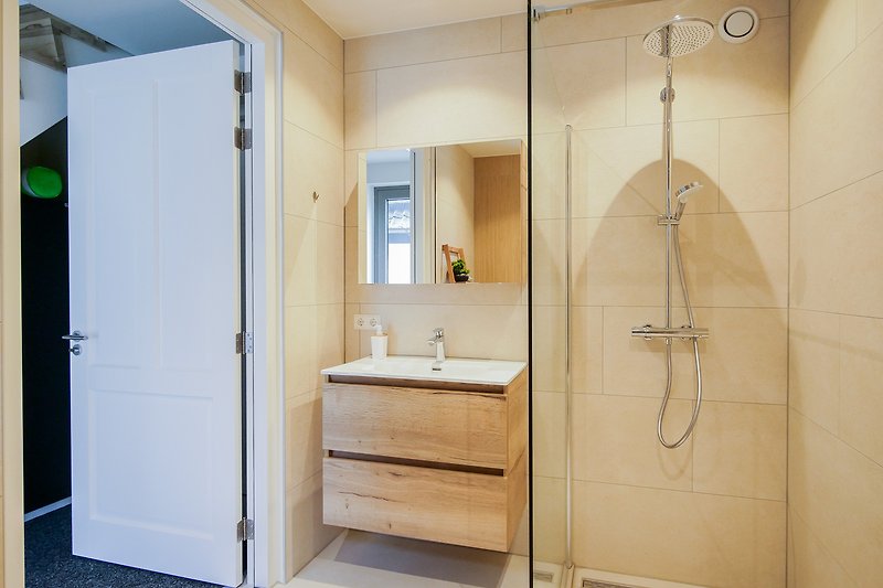 Modernes Badezimmer mit Dusche, Spiegel und Holztür.
