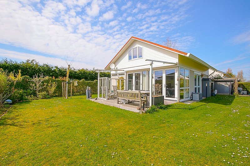 Ländliches Haus mit grünem Garten und blauem Himmel.