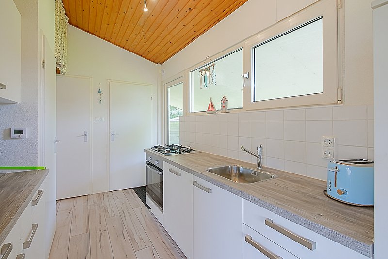 Moderne Küche mit Holzschränken, Spüle und Fenster.