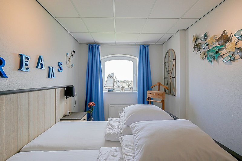 Stilvolles Schlafzimmer mit blauem Bett, Holzmöbeln und Lampen.