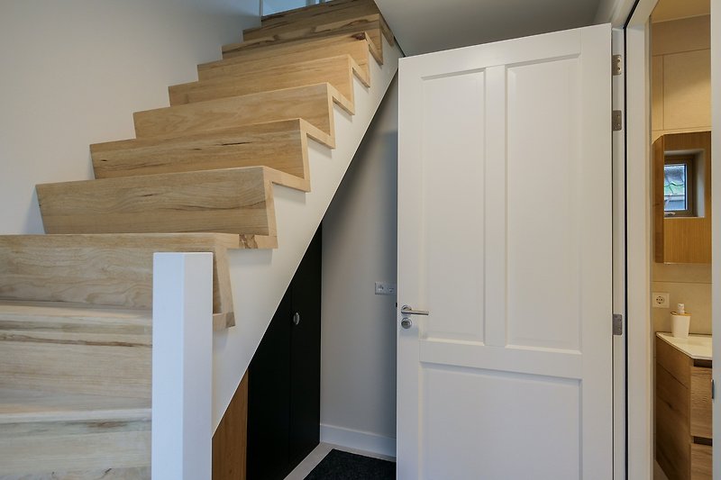 Geräumiger Raum mit Holzverkleidung, Treppe und Glasdetails.