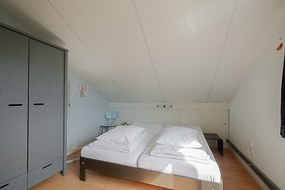 Schlafzimmer mit bequemem Bett, Holzmöbeln und symmetrischer Einrichtung.