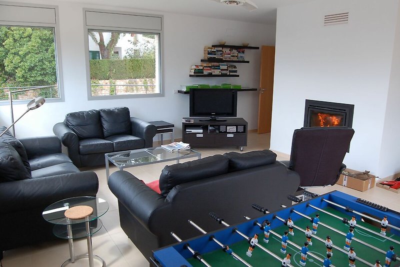 Modernes Wohnzimmer mit Ledermöbel, Kicker, Schwedenofen und großem TV