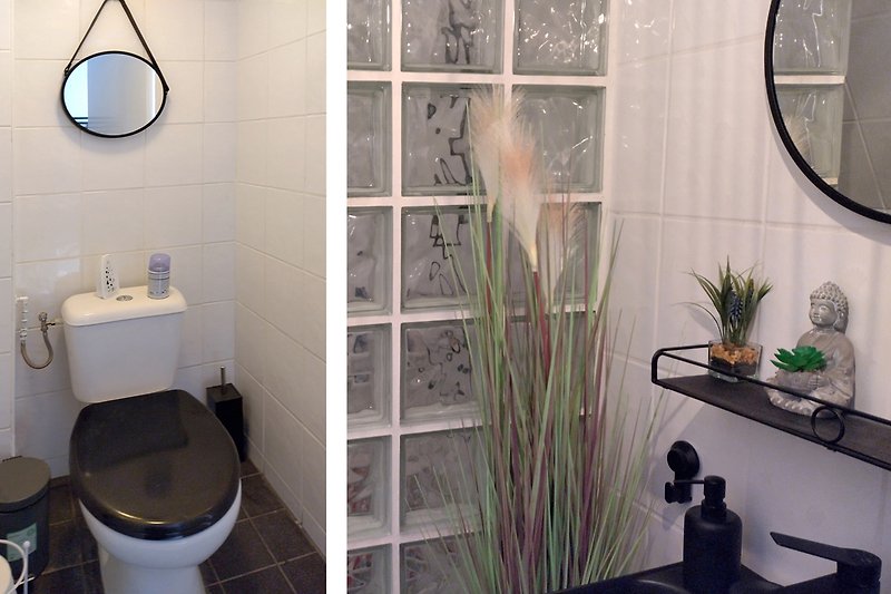 Modernes Badezimmer mit lila Blumentopf und Spiegel.